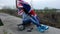 Young women with Union Jack flag sitting with her skateboard on cement lane outdoors