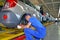 A young worker attaches a part to a car on an assembly line. Car factory