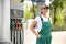 Young worker with fuel pump nozzle at modern gas station