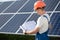 Young worker in overall looking in drawings at solar power station.