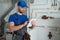 Young worker in a protective suit uses a tablet while checking the boiler equipment in the house.