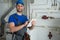 Young worker in a protective suit uses a tablet while checking the boiler equipment in the house.