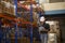 Young worker wearing helmet checking inventory and counting product on shelf in modern warehouse