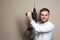 Young working man with rotary hammer on beige background