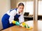 Young workwoman of cleaning service wiping furniture in office