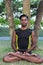 Young yoga man practitioners doing yoga on nature. Asian indian yogis man on the grass in the park. Bali island.