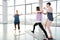 Young yoga trainer helping two active females exercising on mats