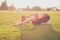 Young yoga trainer is making stretching lying outdoors in spring