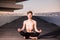 A young yogi places his relaxed hands on his knees during the lotus asana, sitting on wood. Copy space