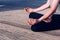 A young yogi places his relaxed hands on his knees during the lotus asana, sitting on wood. Copy space