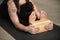 Young yogi woman in paschimottanasana pose with block, close up