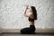 Young yogi woman in vajrasana pose with namaste, loft background