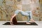 Young yogini practicing Chakrasana variation pose in pastel blue leggins and top