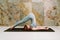 Young yogini practicing Halasana plow pose in pastel blue leggins and top