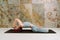 Young yogini practicing Matsyasana pose in pastel blue leggins and top