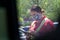 Young youthful fast food worker working at Chick-fil-a drive through amidst cars take orders with tablet