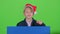 Youngster boy appeared from behind a blue poster points to his index fingers. Green screen