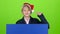 Youngster boy appeared from behind a blue poster points to his index fingers. Green screen. Slow motion