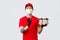 Your order is safe with our couriers. Charismatic delivery guy in red uniform and medical mask, gloves, holding drinks