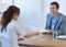 Your resume please. A pretty young woman handing her resume to a prospective employer at a job interview.