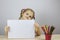 Your text here. Young girl holding a blank sheet of white paper sitting at a table with pencils