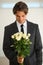 Your valentine in the perfect world. A handsome young man wearing a suit and holding a bunch of roses.