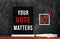 Your Vote Matters text sign on black chalkboard with white notebok and red pen on dark background. Make political choice