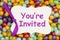 Youre invited message on a gift tag over colorful jellybean candy