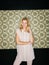 Youre never fully dressed without a smile. a young woman posing against a wallpaper background.