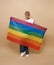 Youth asian transgender LGBT showing Rainbow flag isolated over nude color background. gender expression pride and equality
