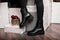 Youth fashionable leather black women`s winter boots. Young woman in jeans in trendy shoes stands in a room near the holiday boxe