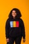 Youth street fashion concept - Confident sexy black woman in stylish hoodie having fun on yellow background.