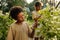 Youthful African American boy standing between green blooming bushes