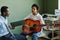 Youthful African American schoolgirl playing acoustic guitar at lesson