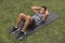 A youthful asian man does a set of ab crunches on a mat at his yard outdoors. Core workout