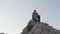 A youthful young shaman in the lotus position prays on a rock against the backdrop of sunset among the sand dunes of the