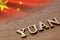 yuan word concept made of wooden letters on wooden background with Chinese flag