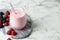 Yummy berry smoothie in glass on white marble table, space for text