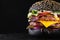 Yummy black burger grilled with double meat cutlet and melted cheese on a black background.