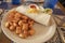 Yummy breakfast burrito and cubed fried potatoes on a plate on a tile table in a resturant