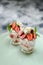 Yummy British dessert Eton mess with raw strawberries, cream and meringues in glasses in green plate side view