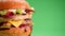 Yummy cheeseburger rotation on a green background, copy space.