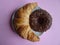 Yummy croissant and chocolate donut on violet background. Top view