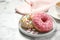 Yummy donuts with sprinkles on marble table, closeup