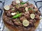 Yummy meat spicey mutton dish in plater made with oil decorate with green chilies and lemons