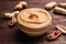 Yummy peanut butter in glass bowl on wooden table, closeup