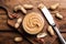 Yummy peanut butter in glass bowl on wooden table, flat lay