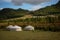 Yurt camp surrounded by trees on the ridge of the mountain. Small ger huts on the crest of the hill on a sunny day