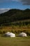 Yurt camp surrounded by trees on the ridge of the mountain. Small ger huts on the crest of the hill on a sunny day