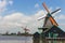 Zaanse Schans, Netherlands - 06/14/2019: Old dutch windmills in historical village. Wooden windmills in field with river.